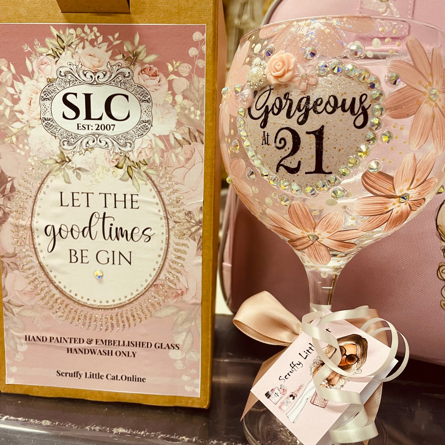 Decorative hand painted and embellished glass with 'Gorgeous at 21' text and embellishments next to a box with 'SLC' branding and text.